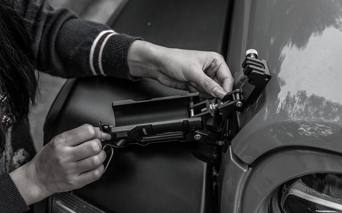 Outdoor view of Jeep Wrangler on grass field equipped with IRURI door-off hood latch mirror system.